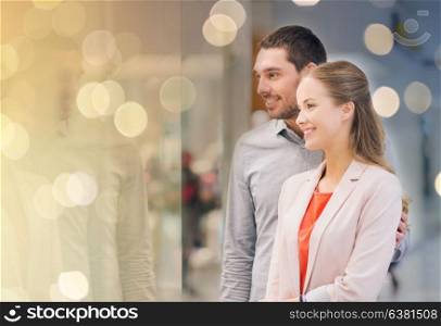sale, consumerism and people concept - happy young couple looking to shop window in mall. happy couple looking to shop window in mall