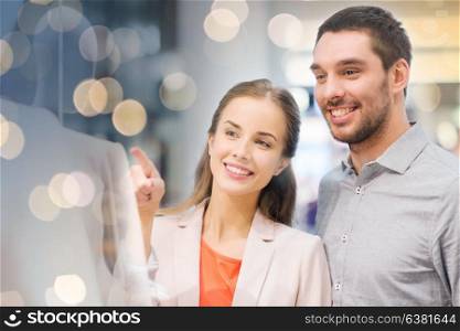 sale, consumerism and people concept - happy young couple pointing finger to shop window in mall. happy couple pointing finger to shop window