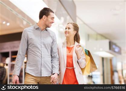 sale, consumerism and people concept - happy young couple with shopping bags walking and talking in mall