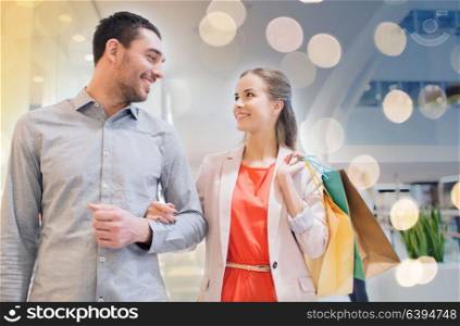 sale, consumerism and people concept - happy young couple with shopping bags walking and talking in mall. happy young couple with shopping bags in mall