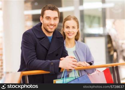 sale, consumerism and people concept - happy young couple with shopping bags in mall