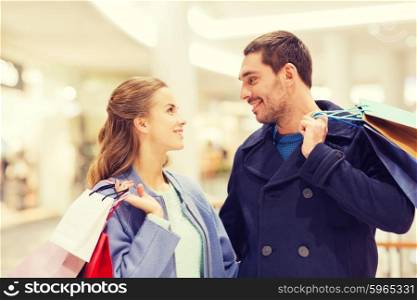 sale, consumerism and people concept - happy young couple with shopping bags talking in mall