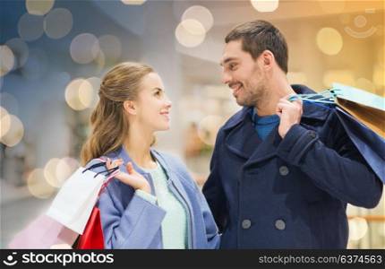 sale, consumerism and people concept - happy young couple with shopping bags talking in mall. happy young couple with shopping bags in mall