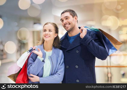 sale, consumerism and people concept - happy young couple with shopping bags walking in mall. happy young couple with shopping bags in mall