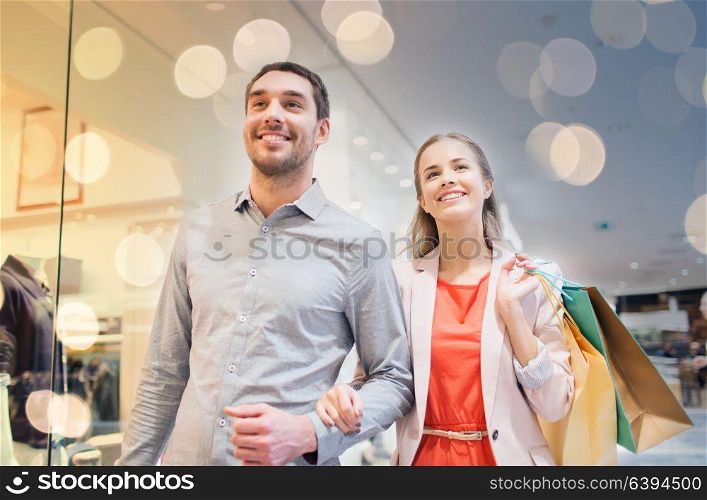 sale, consumerism and people concept - happy young couple with shopping bags walking in mall. happy young couple with shopping bags in mall