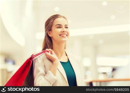 sale, consumerism and people concept - happy young woman with shopping bags in mall
