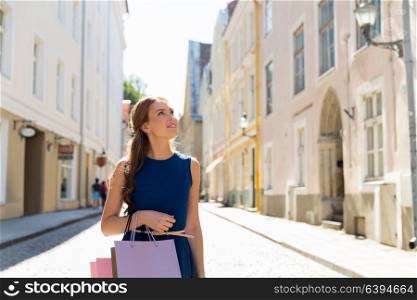 sale, consumerism and people concept - happy young woman with shopping bags on city street. happy woman with shopping bags on city street