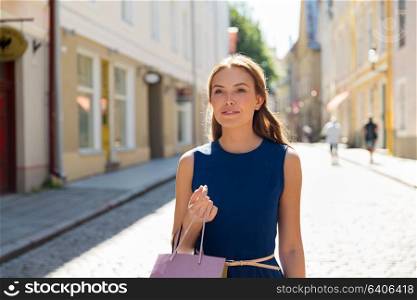 sale, consumerism and people concept - happy young woman with shopping bags on city street. happy woman with shopping bags on city street