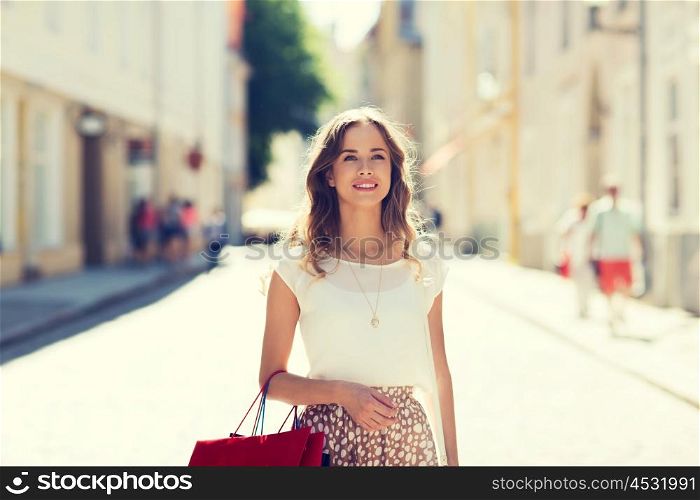 sale, consumerism and people concept - happy young woman with shopping bags walking along city street