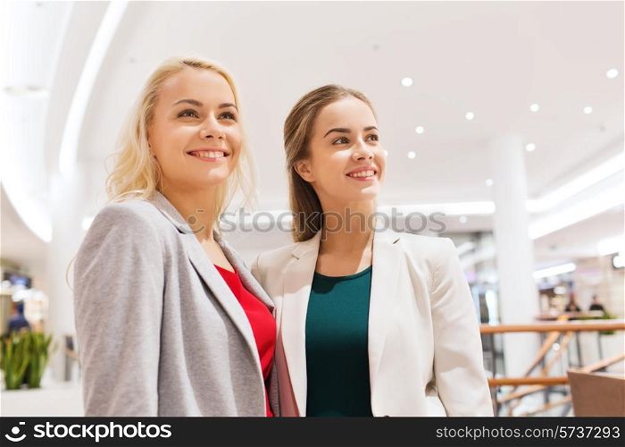 sale, consumerism and people concept - happy young women in mall or business center