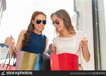 sale, consumerism and people concept - happy young women looking into shopping bags outdoors. happy women looking into shopping bags outdoors