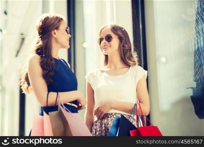 sale, consumerism and people concept - happy young women with shopping bags talking at to shop window in city