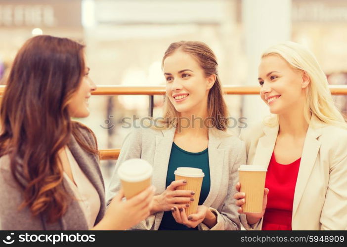 sale, consumerism and people concept - happy young women with shopping bags and coffee paper cups in mall