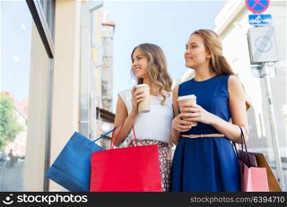 sale, consumerism and people concept - happy young women with shopping bags and coffee takeout at storefront. happy women with shopping bags and coffee outdoors