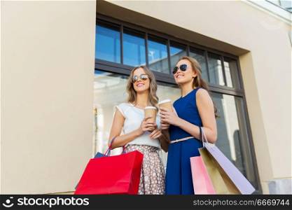 sale, consumerism and people concept - happy young women with shopping bags and coffee takeout at storefront. happy women with shopping bags and coffee outdoors. happy women with shopping bags and coffee outdoors