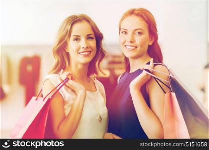 sale, consumerism and people concept - happy young women with shopping bags at clothing shop. happy women with shopping bags at clothing shop