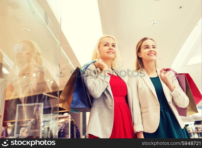 sale, consumerism and people concept - happy young women with shopping bags in mall