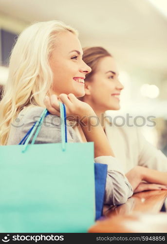 sale, consumerism and people concept - happy young women with shopping bags in mall