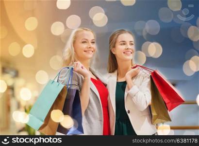 sale, consumerism and people concept - happy young women with shopping bags in mall. happy young women with shopping bags in mall