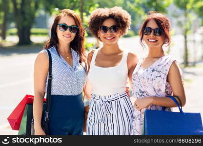 sale, consumerism and people concept - happy young women with shopping bags on city street. happy women with shopping bags in city