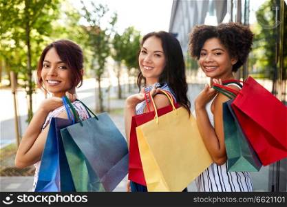 sale, consumerism and people concept - happy young women with shopping bags on city street. happy women with shopping bags in city