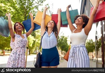 sale, consumerism and people concept - happy young women with shopping bags on city street. happy women with shopping bags in city
