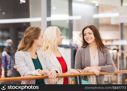 sale, consumerism and people concept - happy young women with shopping bags talking in mall