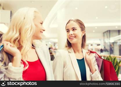 sale, consumerism and people concept - happy young women with shopping bags talking in mall
