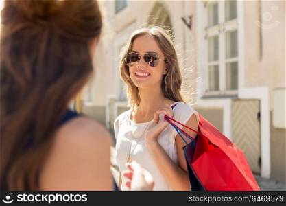 sale, consumerism and people concept - happy young women with shopping bags talking on city street. happy women with shopping bags at storefront