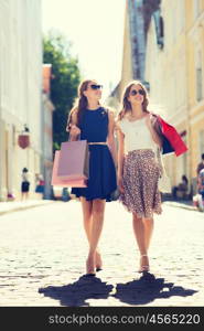 sale, consumerism and people concept - happy young women with shopping bags walking along city street