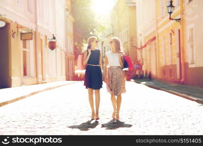 sale, consumerism and people concept - happy young women with shopping bags walking along city street. happy women with shopping bags walking in city