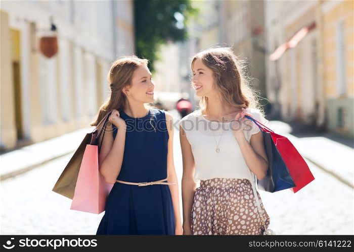 sale, consumerism and people concept - happy young women with shopping bags walking along city street