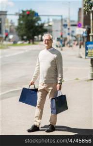 sale, consumerism and people concept - senior man with shopping bags walking in city