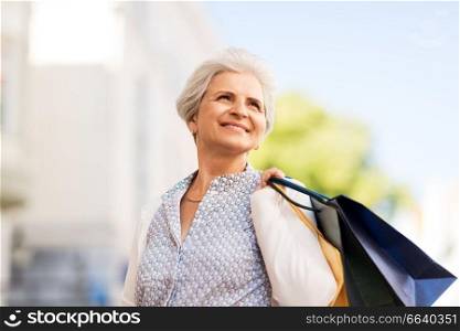 sale, consumerism and people concept - senior woman with shopping bags in city. senior woman with shopping bags in city