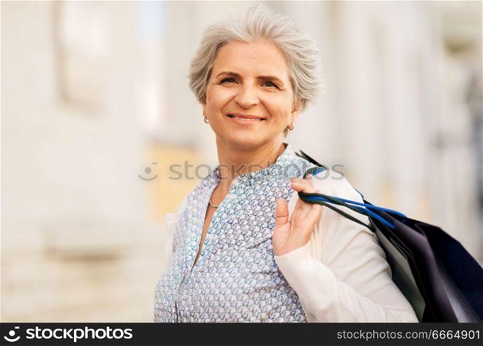 sale, consumerism and people concept - senior woman with shopping bags on city street. senior woman with shopping bags on city street