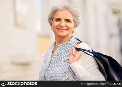sale, consumerism and people concept - senior woman with shopping bags on city street. senior woman with shopping bags on city street