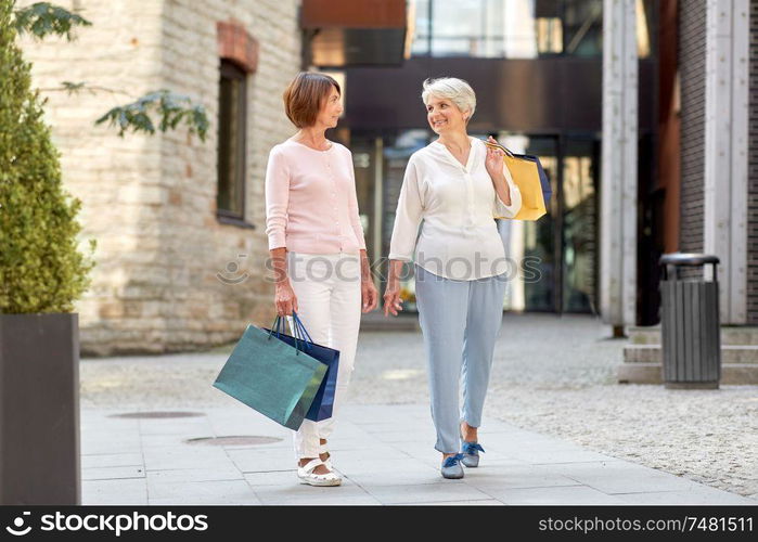 sale, consumerism and people concept - two senior women or friends with shopping bags walking along tallinn city street. senior women with shopping bags walking in city