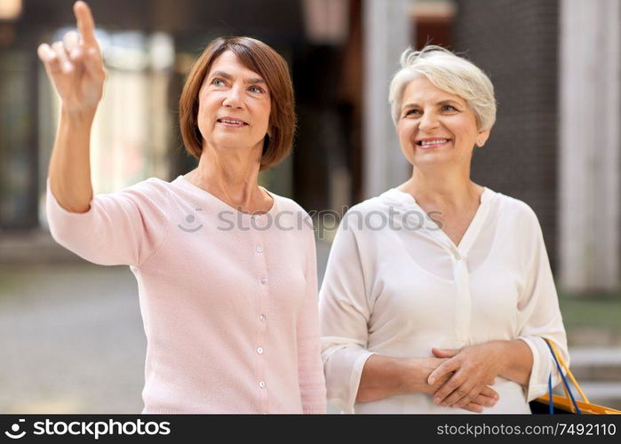 sale, consumerism and people concept - two senior women or friends with shopping bags on tallinn city street. senior women with shopping bags in tallinn city