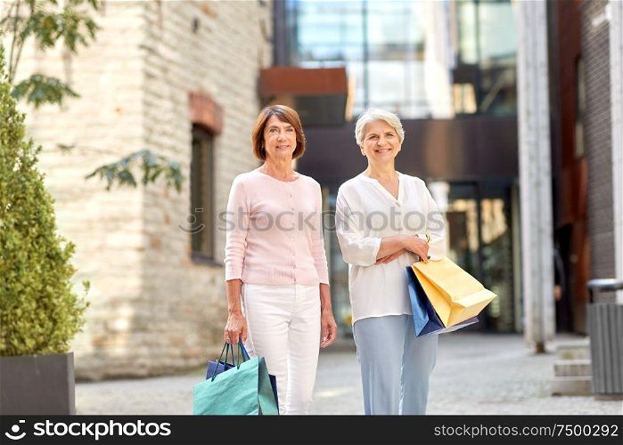 sale, consumerism and people concept - two senior women or friends with shopping bags on tallinn city street. senior women with shopping bags in tallinn city