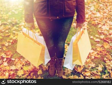 sale, consumerism, season and people concept - woman with shopping bags in autumn park. woman with shopping bags in autumn park
