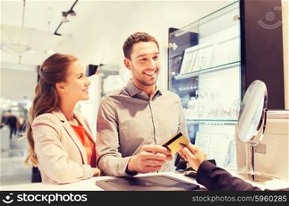 sale, consumerism, shopping and people concept - happy couple with credit card at jewelry store in mall
