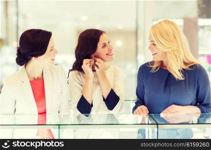 sale, consumerism, shopping and people concept - happy happy women choosing and trying on earrings at jewelry store