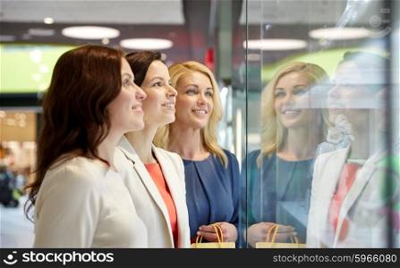 sale, consumerism, shopping and people concept - happy women looking at jewelry shop window in mall