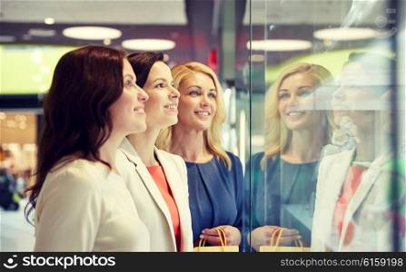 sale, consumerism, shopping and people concept - happy women looking at jewelry shop window in mall
