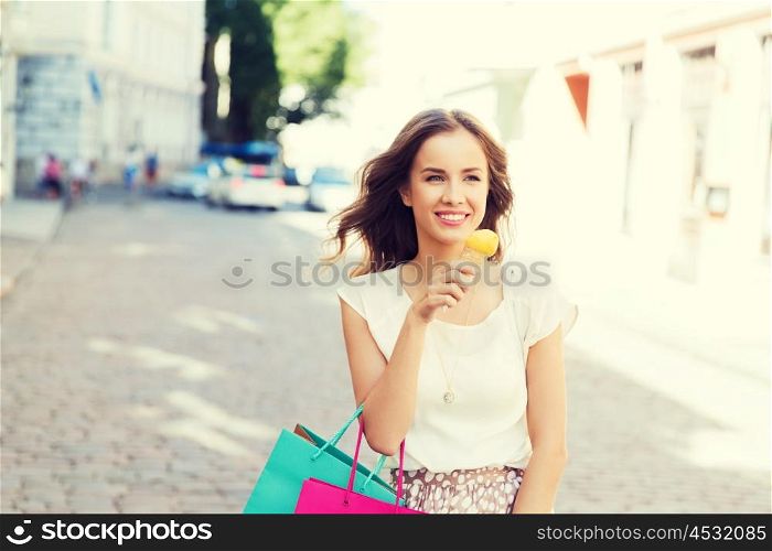 sale, consumerism, summer and people concept - happy young woman with shopping bags and ice cream on city street