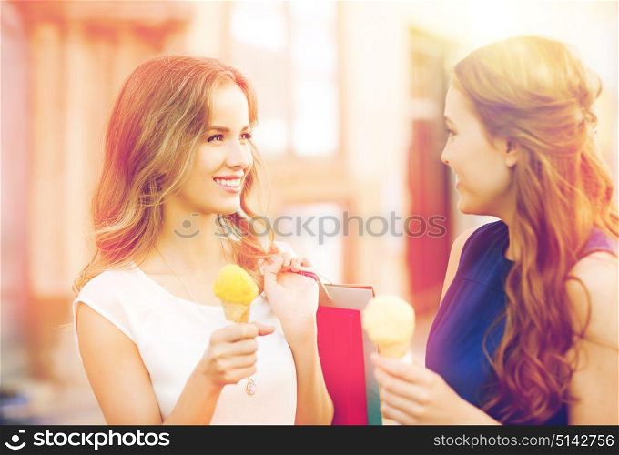 sale, consumerism, summer and people concept - happy young women with shopping bags and ice cream talking on city street. woman with shopping bags and ice cream in city