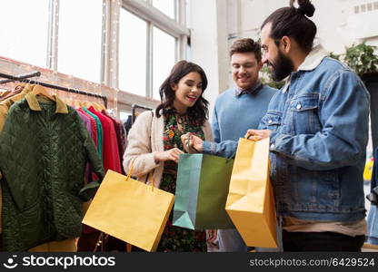 sale, fashion and people concept - happy friends with shopping bags at vintage clothing store. friends shopping bags at vintage clothing store