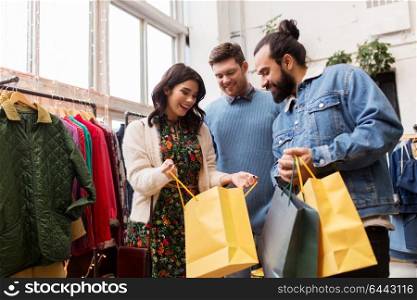 sale, fashion and people concept - happy friends with shopping bags at vintage clothing store. friends shopping bags at vintage clothing store