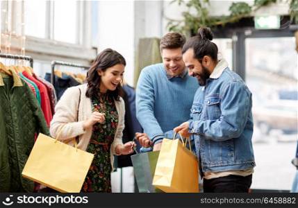 sale, fashion and people concept - happy friends with shopping bags at vintage clothing store. friends shopping bags at vintage clothing store
