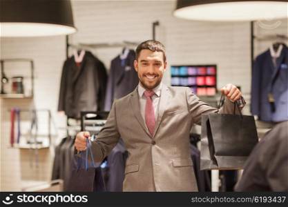 sale, fashion, retail, business style and people concept - happy man with shopping bags at clothing store